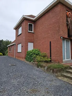a red brick house with a window and a driveway at Bianca's vakantiehuis in Houthalen-Helchteren