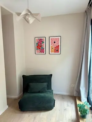 a living room with a green ottoman and a ceiling fan at Studio Auguste in Liège
