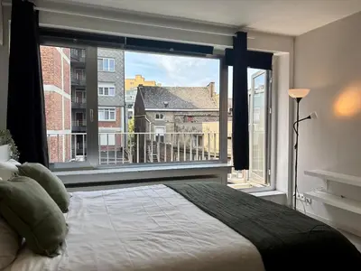 a bedroom with a bed and a large window at Le studio de la Cathédrale - Hypercentre avec balcon in Liège