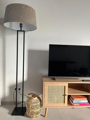 a floor lamp in a living room with a television at Le Cabinet in Liège