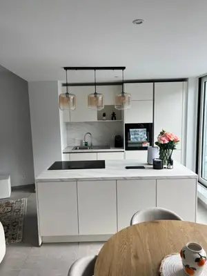 a kitchen with white cabinets and a table and chairs at Appart lumineux avec terrasse au cœur de Liège in Liège