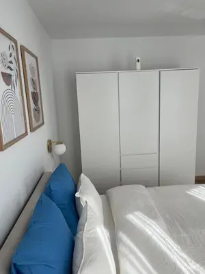 a bed with blue pillows in a white bedroom at Appart lumineux avec terrasse au cœur de Liège in Liège