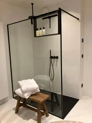 a glass shower stall with a bench in a bathroom at Het Huisje in Tongeren