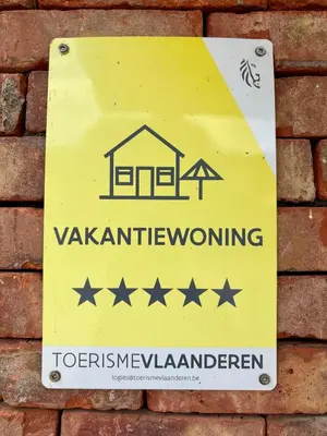 a sign on the side of a brick wall at Vakantiewoning De Vliergeit in Limburg - Haspengouw in Hasselt