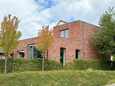 a brick building with trees in front of it at Vakantiewoning De Vliergeit in Limburg - Haspengouw in Hasselt