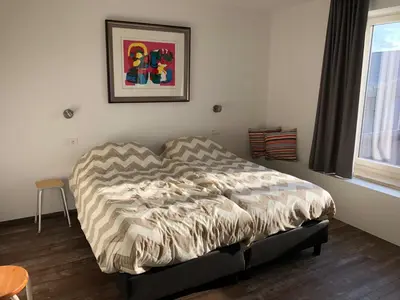 a bed in a bedroom with a picture on the wall at Vakantiewoning De Vliergeit in Limburg - Haspengouw in Hasselt