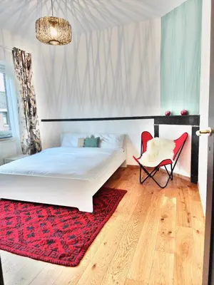 a bedroom with a white bed and a red rug at Maison spacieuse, sereine proche du coeur de la ville et de la gare in Liège
