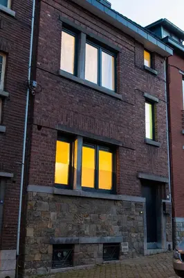 a brick building with yellow lights in the windows at Maison spacieuse, sereine proche du coeur de la ville et de la gare in Liège