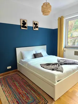 a bedroom with a bed with a blue wall at Maison spacieuse, sereine proche du coeur de la ville et de la gare in Liège