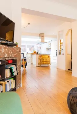 a living room with a hard wood floor and a kitchen at Maison spacieuse, sereine proche du coeur de la ville et de la gare in Liège
