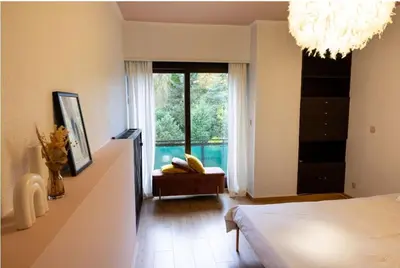 a bedroom with a bed and a large window at Maison modernisée au caractère 70ies in Herstal