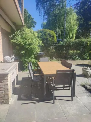 a wooden table and chairs on a patio at Maison modernisée au caractère 70ies in Herstal