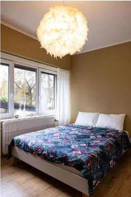 a bedroom with a bed and a chandelier at Maison modernisée au caractère 70ies in Herstal