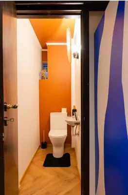 a bathroom with a white toilet and an orange wall at Maison modernisée au caractère 70ies in Herstal