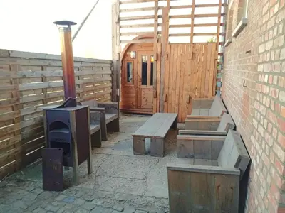 a patio with benches and a grill and a wooden door at Farmhouse with garden and wellness in Heers