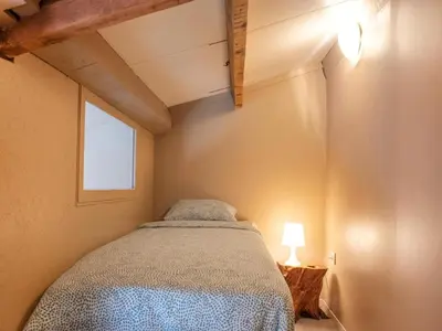 a small bedroom with a bed and a lamp at Cozy duplex apartment with terrace in Heers
