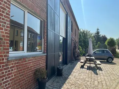 a car parked next to a brick building with an umbrella at Apartment with a view of alpacas in Heers