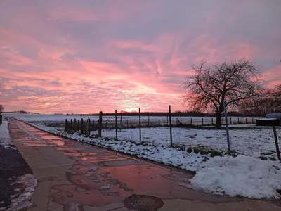 a snowy sidewalk with a sunset in the background at Holiday home with garden and roofed terrace in Heers