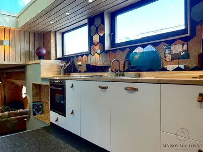 a kitchen with a counter with a sink and windows at La péniche de Santa Cruz - Sur la Meuse, centre ville in Liège