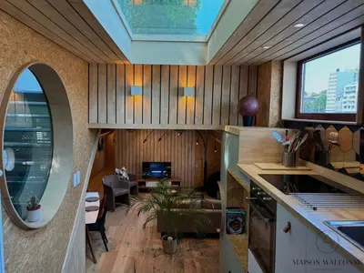 a kitchen with a vaulted ceiling and a living room at La péniche de Santa Cruz - Sur la Meuse, centre ville in Liège