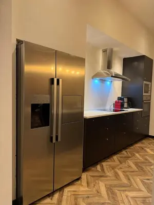 a stainless steel refrigerator in a kitchen with wooden floors at Premium apartment at the gates of Liège in Liège