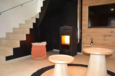 a living room with two stools and a fireplace at Maison au coeur du village in Aubel