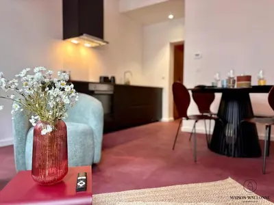 a living room with a red vase with flowers on a table at Le Red Velvet - Hypercentre, pour 2 personnes in Liège