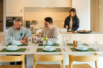 three people sitting at a table in a kitchen at Woodz Lodges - Unwind in nature in Heusden - Zolder