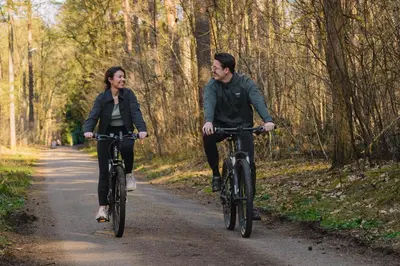 a man and woman riding bikes down a trail at Woodz Lodges - Unwind in nature in Heusden - Zolder