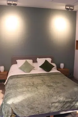 a bedroom with a large bed with two green pillows at Le Chen Zen in Dalhem