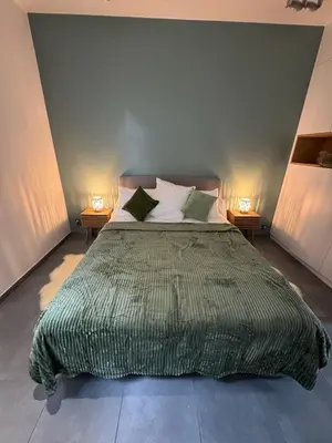 a bed with a green comforter in a bedroom at Le Chen Zen in Dalhem