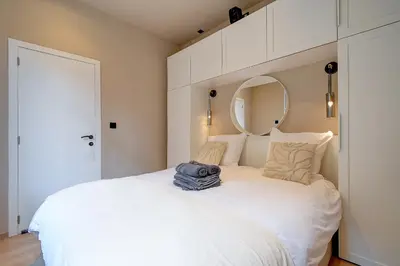 a bedroom with a large white bed with a mirror at L'Escapade in Liège