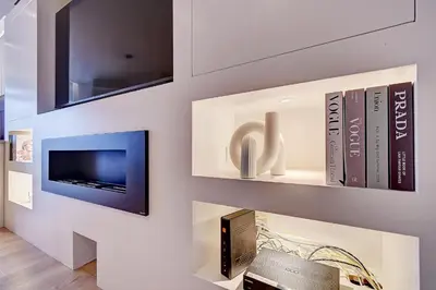 a living room with a tv and books on a wall at L'Escapade in Liège
