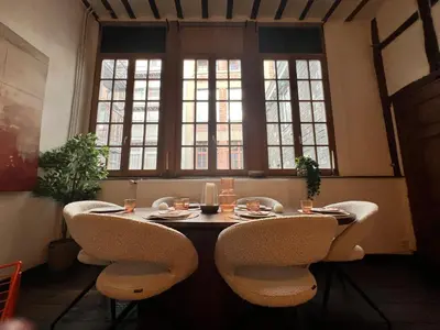 a table in a room with chairs and windows at Clémentine - 3 chambres en Hypercentre in Liège