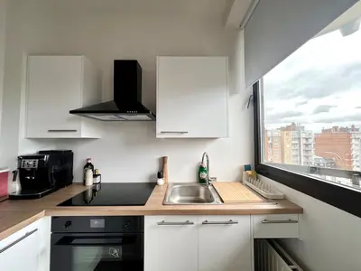 a kitchen with white cabinets and a sink and a window at Avenue Rogier in Liège