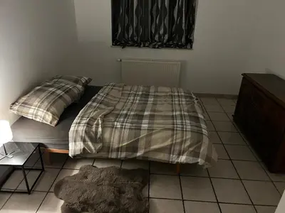 a bedroom with a bed with a plaid blanket on it at Grâce à Liège in Grâce-Hollogne