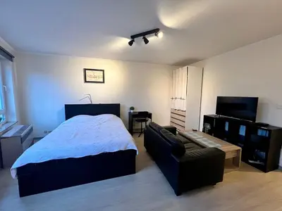 a bedroom with a bed and a couch at Le studio de la Boverie - Entièrement équipé in Liège
