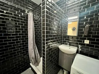 a black tiled bathroom with a sink and a toilet at Le studio de la Boverie - Entièrement équipé in Liège