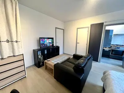 a living room with a couch and a flat screen tv at Le studio de la Boverie - Entièrement équipé in Liège