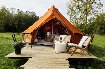 a tent with chairs and a table in a field at Glamping Chateau d'Hamont in Herk-de-Stad
