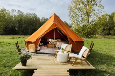 a tent with a bed and chairs in a field at Glamping Chateau d'Hamont in Herk-de-Stad