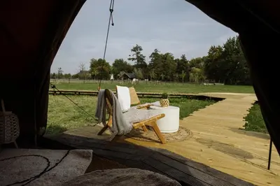 a tent with a chair sitting on a wooden deck at Glamping Chateau d'Hamont in Herk-de-Stad