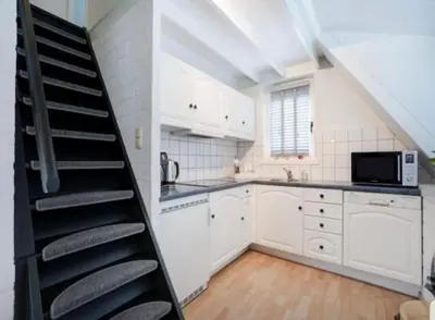 a kitchen with a spiral staircase in a loft at Boshuisje Rekem Charly in Lanaken