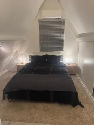 a bedroom with a large black bed with two lamps at Boshuisje Rekem Charly in Lanaken
