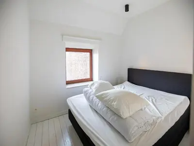 a bed with white sheets and a window in a room at Holiday home in the heart of Hasselt in Hasselt