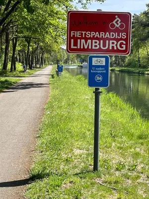 a sign on the side of a road next to a river at B&B De Zandput in Balen