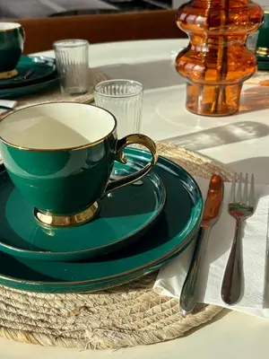 a green coffee cup on a green plate on a table at Vintage Station in Ans