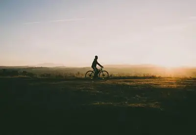 a person riding a bike on a field at sunset at Camping Papillon Kinrooi - Vakantiehuis Familie 6P in Kinrooi