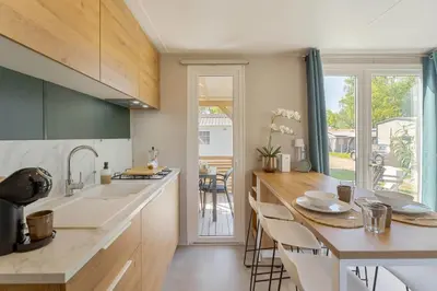 a kitchen with a sink and a counter with chairs at Camping Papillon Kinrooi - La Casetta in Kinrooi