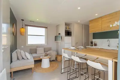a kitchen and living room with a bar and a couch at Camping Papillon Kinrooi - La Casetta in Kinrooi